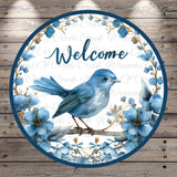 A blue bird perched on a branch, surrounded by blue flowers and leaves, with the word "Welcome" written in cursive above it.