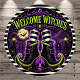 A circular sign with the text "WELCOME WITCHES" and a pair of witch's boots against a purple and green background with bats, a full moon, and a castle.