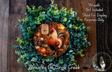 a wreath with a rooster and autumn-themed decorations, including pumpkins, gourds, and a lantern. The wreath is displayed on a wooden surface, and there is a small dog in the bottom right corner.