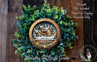 A wreath made of evergreen branches and a circular frame with a winter scene and the text "Merry Christmas" on it.