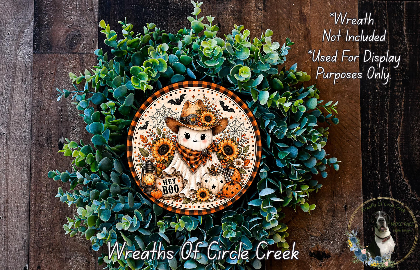 a wreath with a ghost wearing a cowboy hat and scarf, surrounded by green foliage and orange and black decorations.