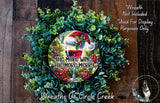a wreath made of green leaves and red berries, with a wine glass and a red and white plaid hat on top. The wreath is displayed on a wooden surface, and there is a text overlay that reads &quot;The more wine, the merrier&quot; and &quot;Wreaths of Circle Creek&quot;.