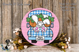 a round wooden sign with a cartoon illustration of a bunny in a truck, surrounded by flowers and a "Happy Easter" sign.