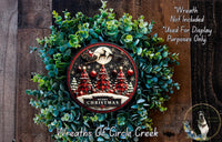A Christmas wreath made of evergreen branches and topped with a red and white wreath, featuring a Santa Claus sleigh and a full moon.