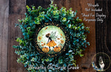 a wreath with a fairy and pumpkins, surrounded by greenery.