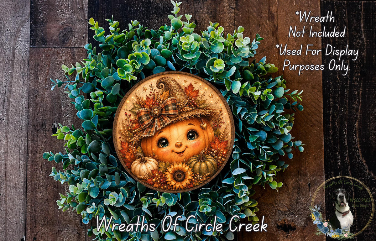 A wreath featuring a pumpkin and sunflowers, with a smiling face, is displayed on a wooden surface.