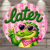 A green alligator wearing sunglasses and a pink bow tie is making a peace sign with its right hand against a pink background with stars and the word "later" written in green.