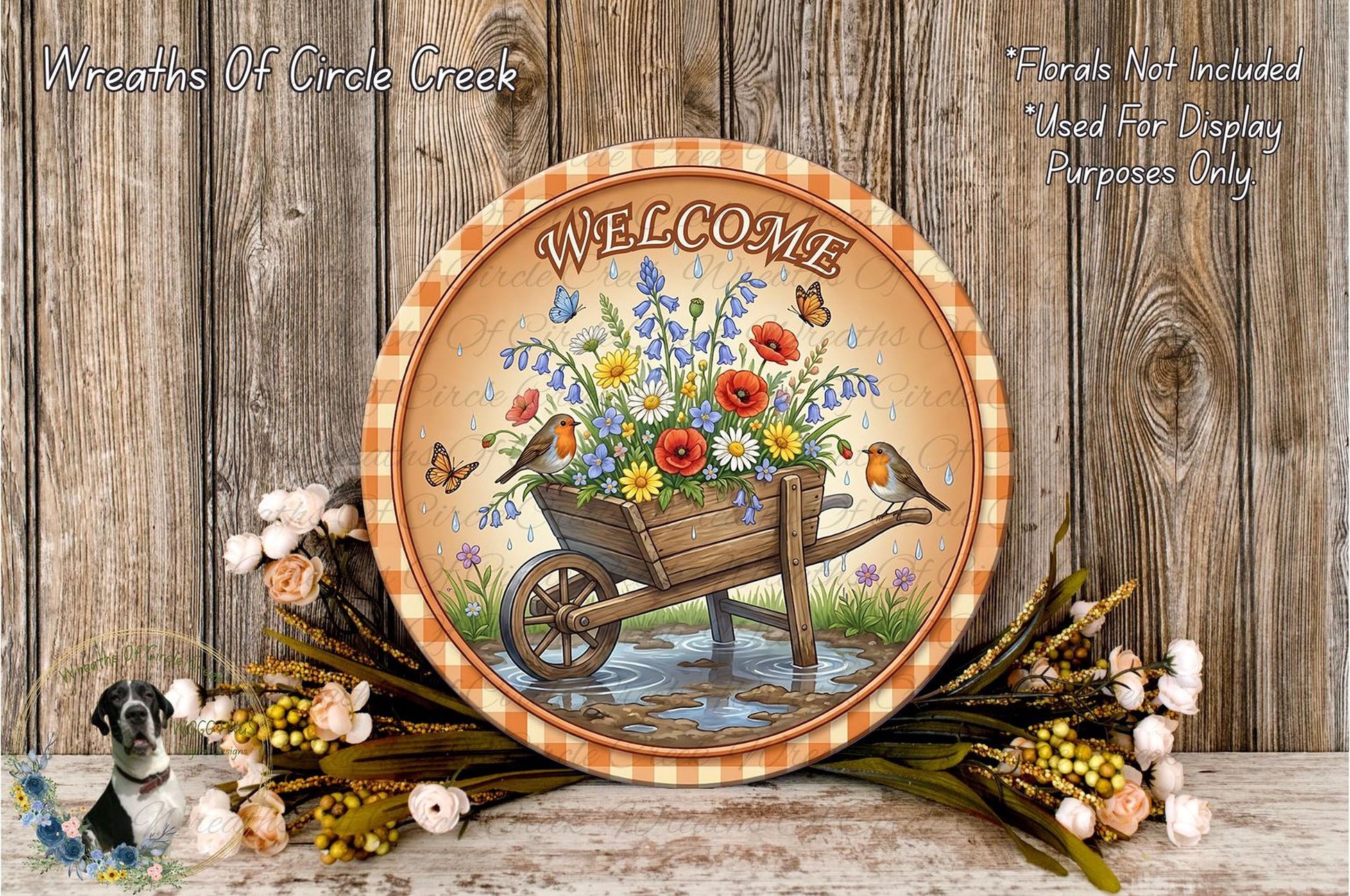 a round sign with a wagon wheel and flowers, surrounded by a wreath of flowers and a bird. The sign has the word "Welcome" written on it.