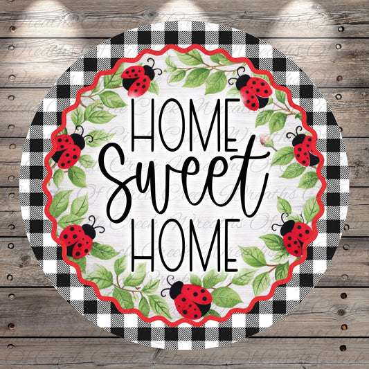 a circular design with a black and white checkered border and a wreath of green leaves and red ladybugs surrounding the text "HOME SWEET HOME".
