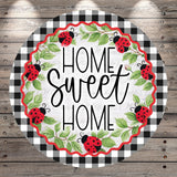 a circular design with a black and white checkered border and a wreath of green leaves and red ladybugs surrounding the text "HOME SWEET HOME".