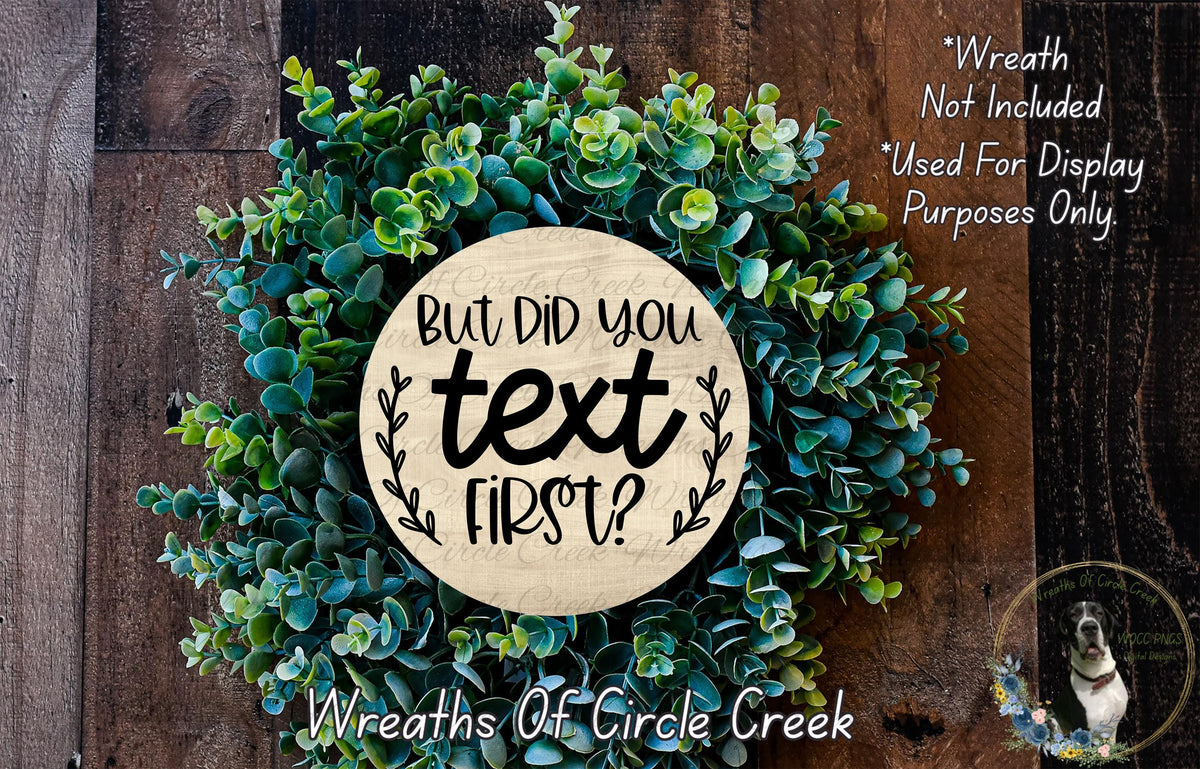 a wreath made of green succulents and a wooden sign with the text "But did you text first?" displayed on it.