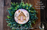 A wreath featuring a gingerbread house surrounded by greenery, with a caption stating that the wreath is not included in a display and is used for purposes only.