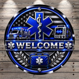 a welcome sign with a blue star of life symbol, flanked by an ambulance and a medical device, all set against a wooden background.