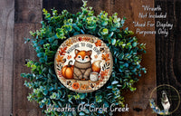 a wreath with a fox wearing a sweater and holding a cup of fall leaves, surrounded by a lush green wreath. The wreath is displayed on a wooden surface, and there is a text overlay that reads "Welcome to Our Home" and "Wreath Not Included Used For Display Purposes Only".