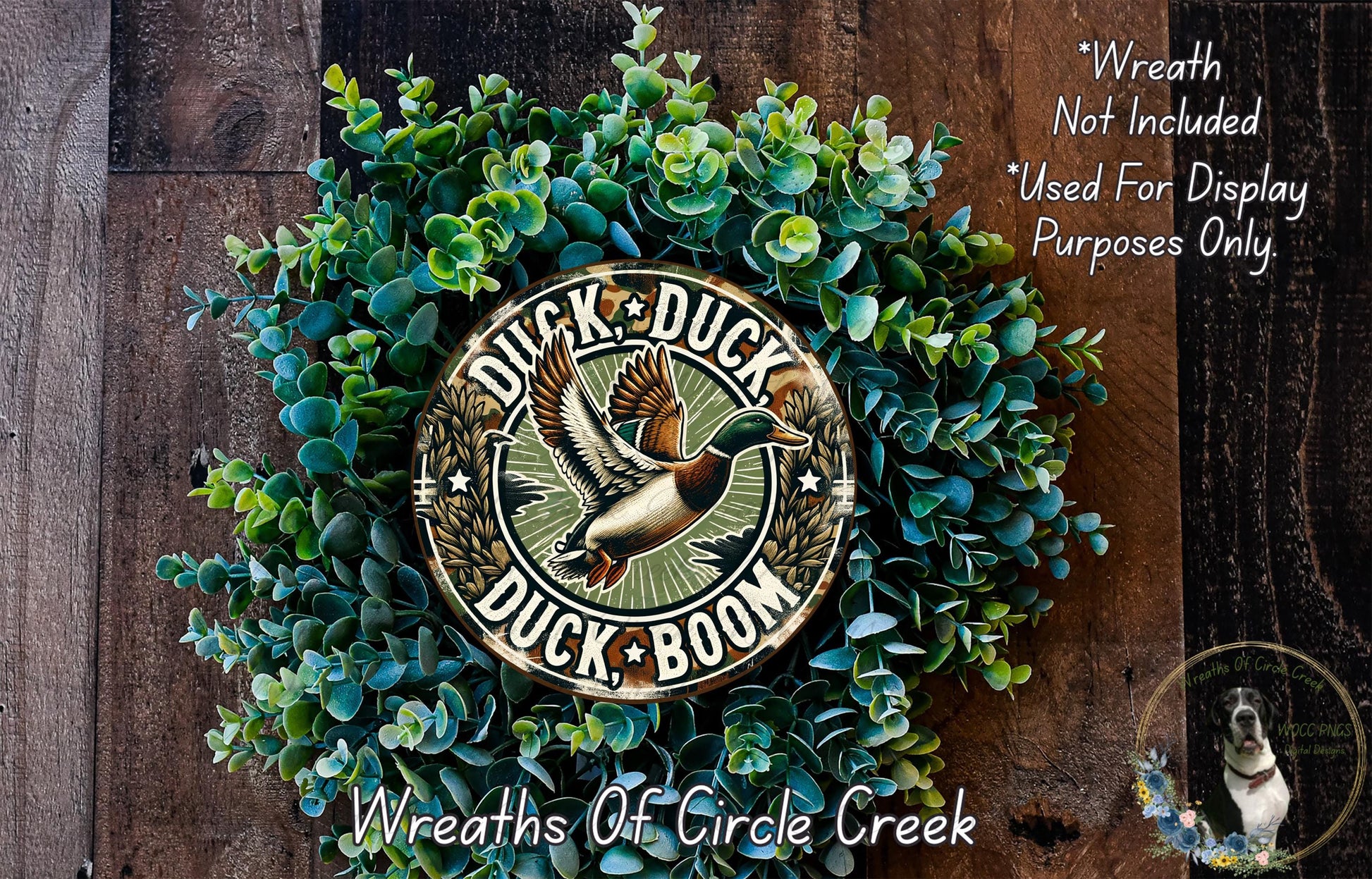 a wreath made of green foliage and a circular sign with the text "Duck, Duck, Duck" and a graphic of a duck in flight. The sign is surrounded by the green foliage, creating a decorative and nature-inspired arrangement.