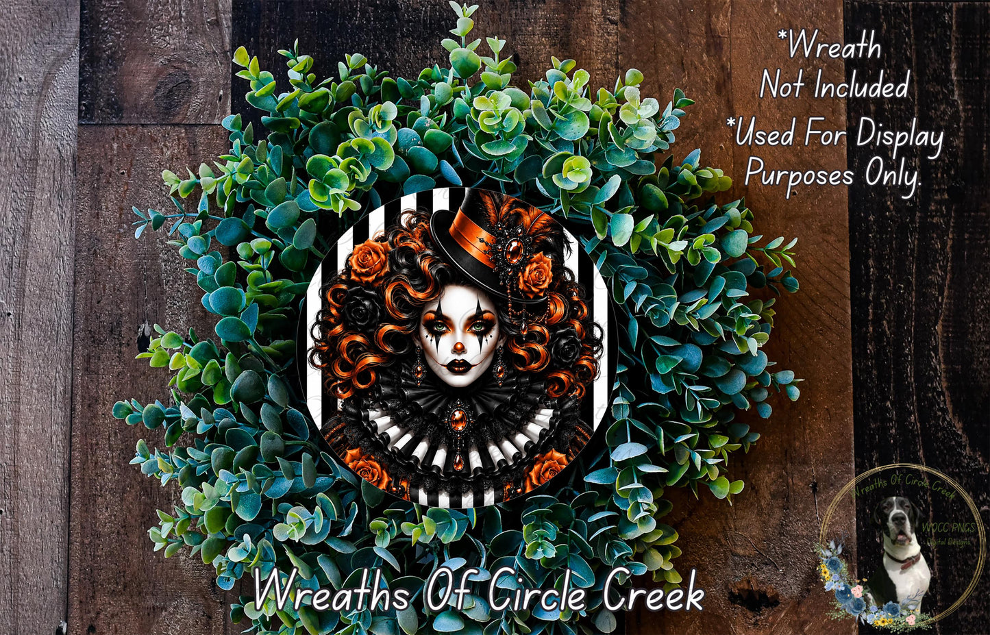 a wreath with a woman's face as the central design element, surrounded by a lush green plant. The wreath is displayed on a wooden surface, and there is a small dog visible in the bottom right corner of the image.