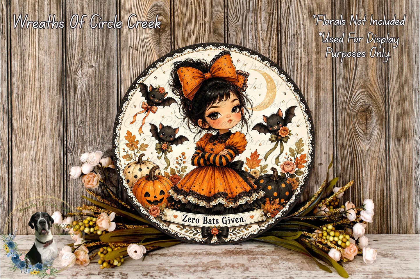 A decorative Halloween-themed wreath featuring a young girl dressed in an orange and black outfit, surrounded by bats, pumpkins, and flowers.