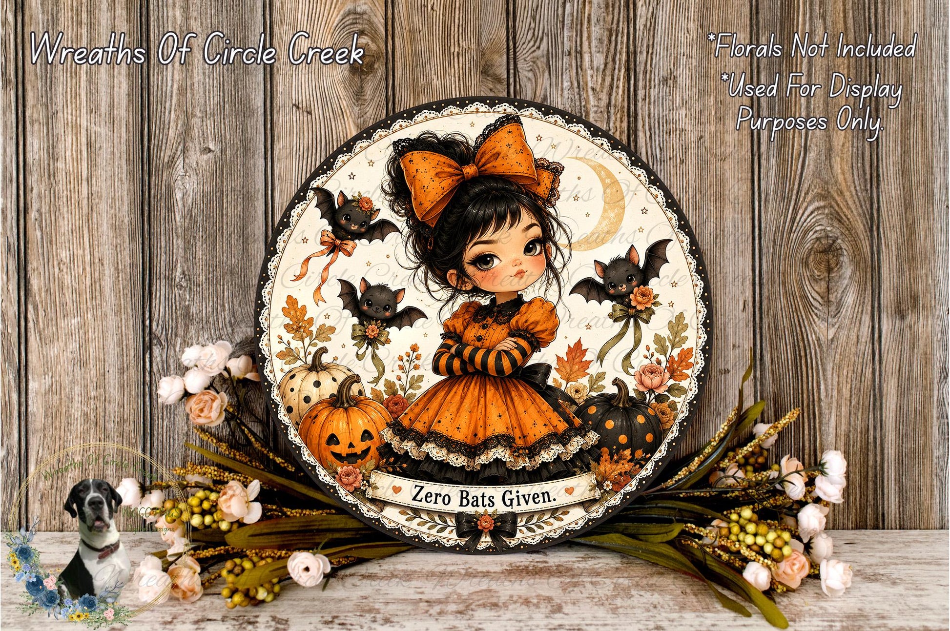 A decorative Halloween-themed wreath featuring a young girl dressed in an orange and black outfit, surrounded by bats, pumpkins, and flowers.