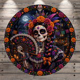 A colorful and intricate Day of the Dead-inspired illustration featuring a skeleton woman with a fan, surrounded by a vibrant floral border and a nighttime cityscape backdrop.