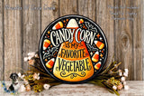 A decorative sign with the text "CANDY CORN is my favorite vegetable" is displayed on a wooden surface, surrounded by a wreath of flowers.