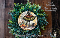 The image is a wreath made of various green plants and a circular plate with a Halloween-themed illustration of a witch. The wreath is displayed on a wooden surface, and there is a text overlay that reads "Wreath Not Included * Used For Display Purposes Only."