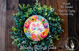 A colorful wreath made of various green plants and flowers, with a circular sign that says "Hello Spring" in the center.