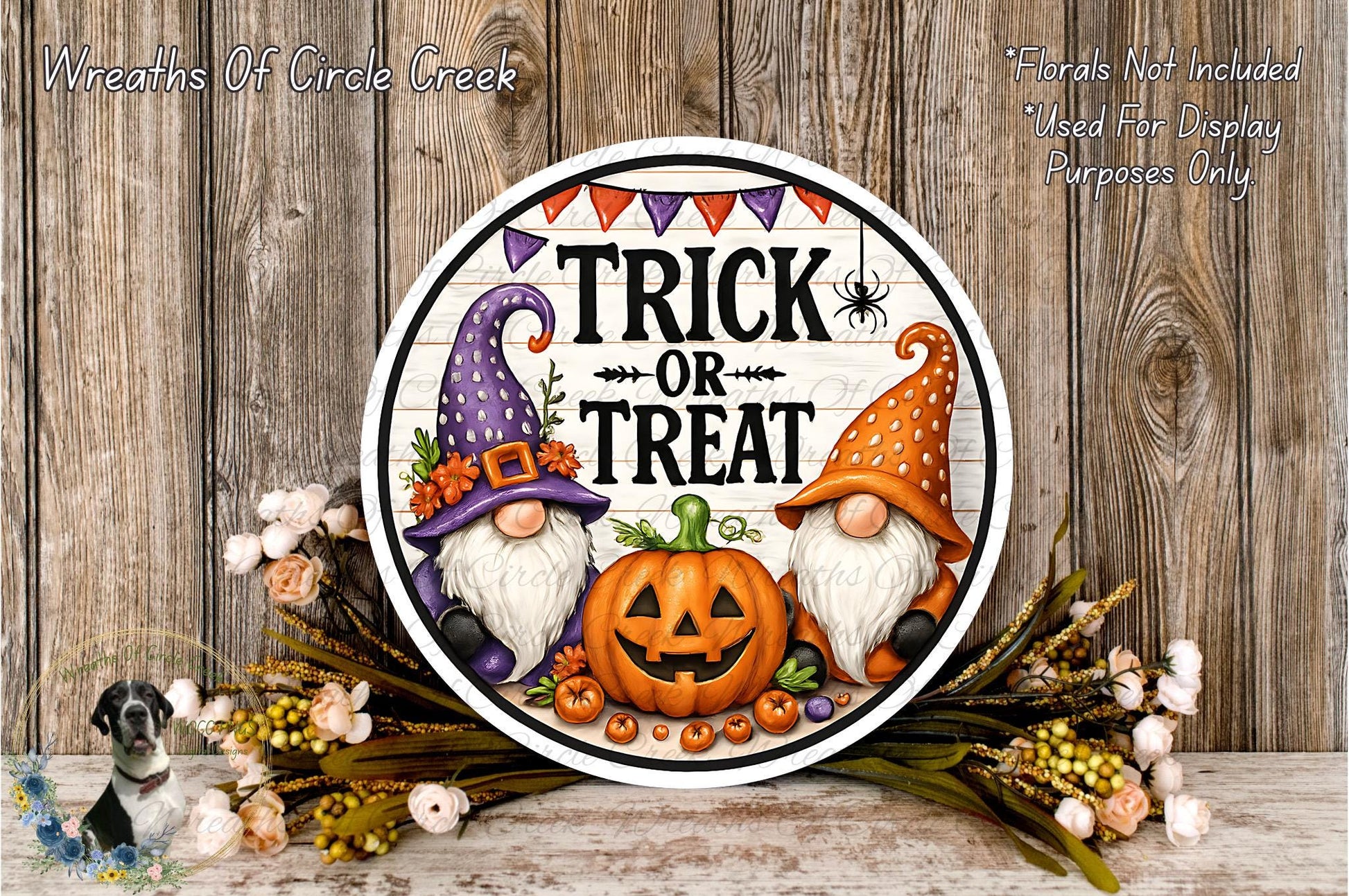a Halloween-themed sign with a pumpkin and two gnomes, surrounded by flowers and a wooden background.