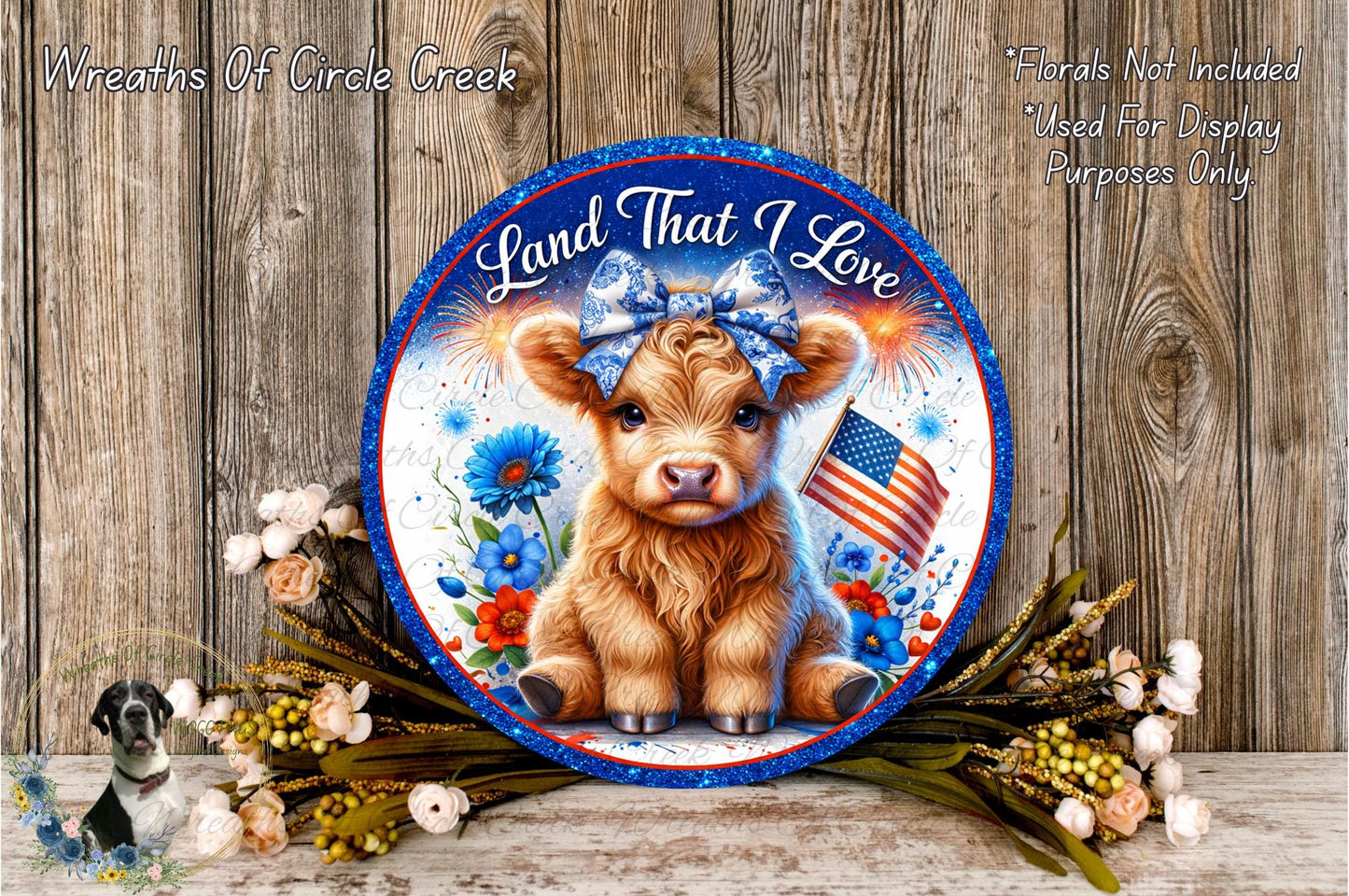 a decorative plate with a cow wearing a blue bow, surrounded by flowers and an American flag, placed on a wooden surface.