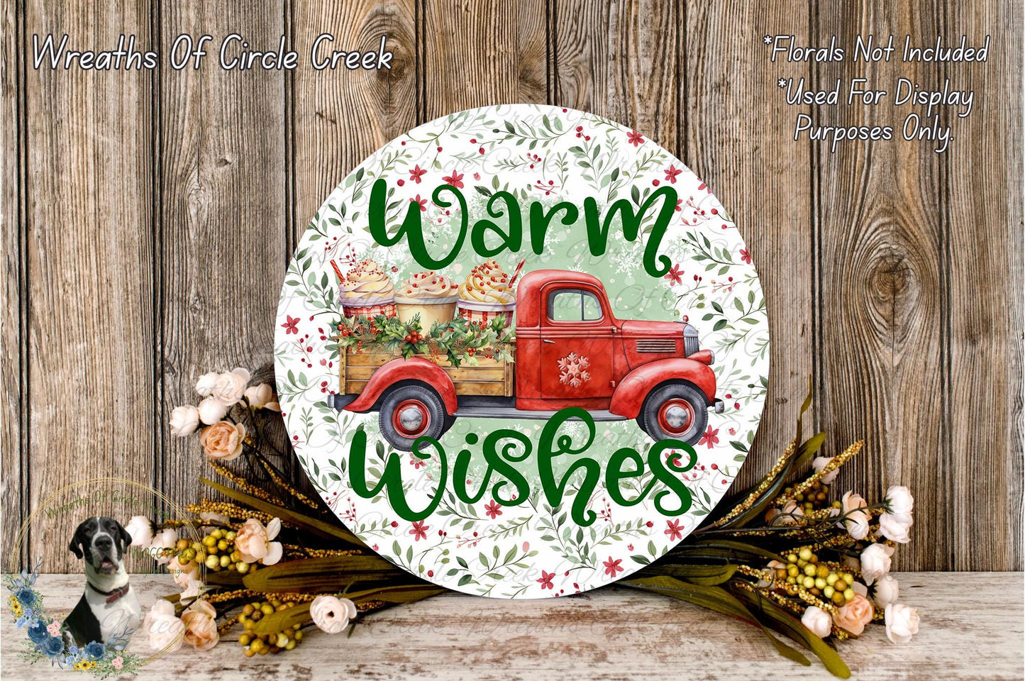 A round wooden sign with a red truck and a floral design, surrounded by flowers and greenery, with the text "Warm Wishes" displayed on it.