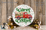 A round wooden sign with a red truck and a floral design, surrounded by flowers and greenery, with the text "Warm Wishes" displayed on it.