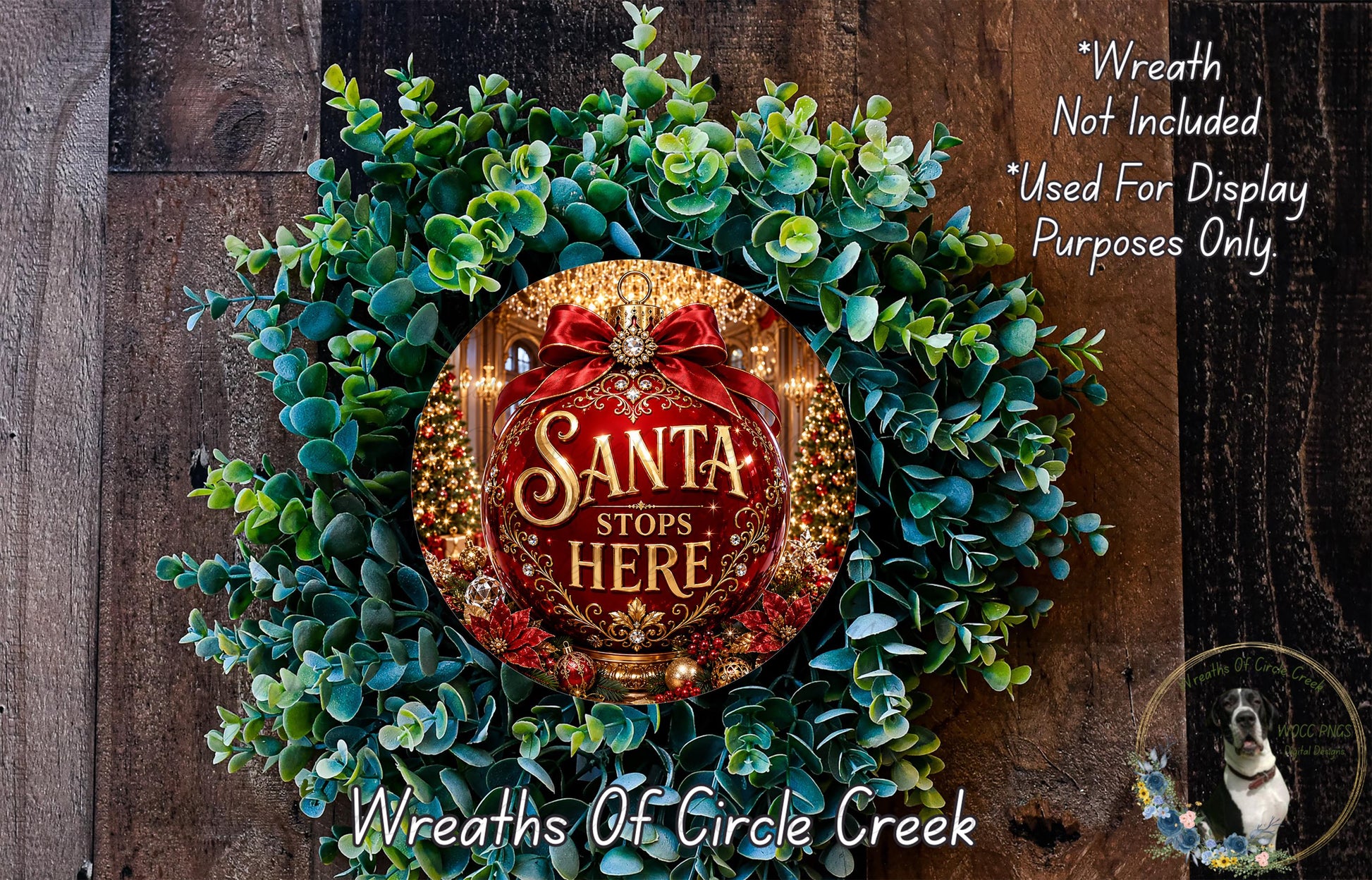 A wreath made of green leaves and a red ribbon with the text "Santa stops here" in the center, placed on a wooden surface.