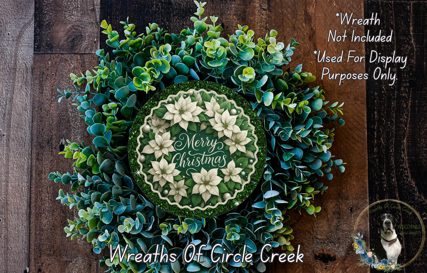A wreath made of various green and white flowers, including poinsettias, placed on a wooden surface. The wreath has a circular design with the text "Merry Christmas" written on it.