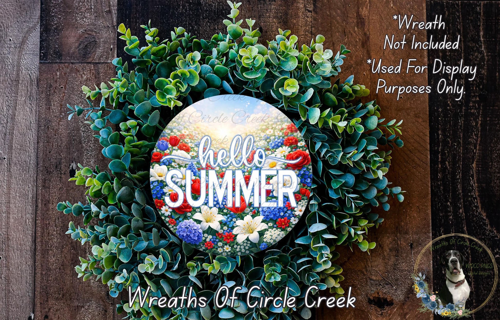 A wreath made of green leaves and flowers, with the text "Hello Summer" displayed on it. The wreath is placed on a wooden surface, and there is a small dog in the bottom right corner of the image.