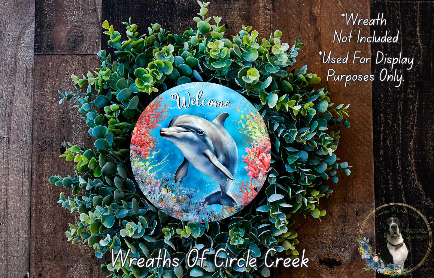 a wreath with a dolphin image, surrounded by greenery, and a welcome sign. The wreath is displayed on a wooden surface, and there is a text overlay that reads "Welcome Not Included * Used For Display Purposes Only".
