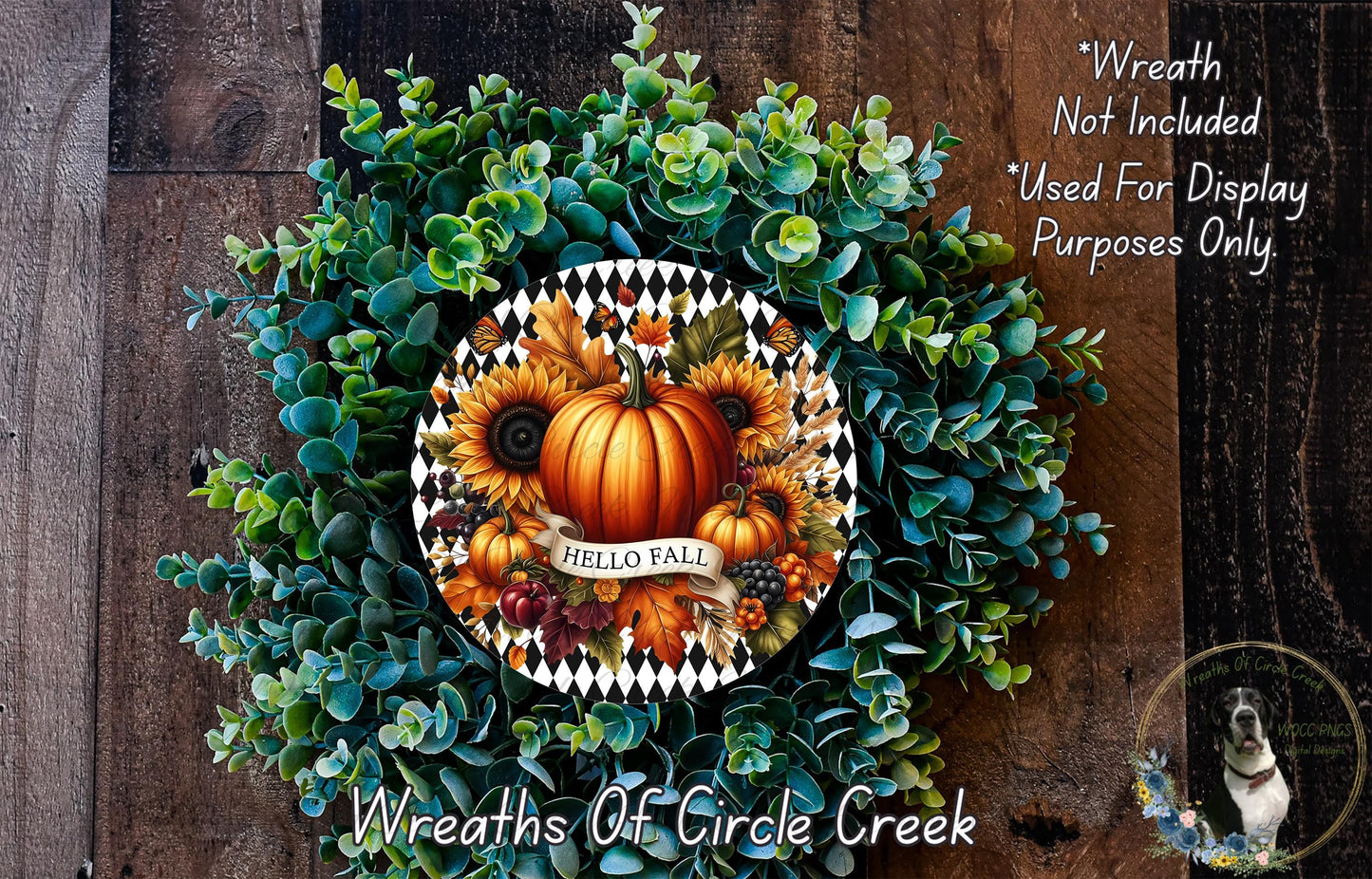 a wreath made of various fall-themed elements, including sunflowers, pumpkins, and a pumpkin with the word "Hello Fall" written on it. The wreath is displayed on a wooden surface, and there is a small dog in the bottom right corner of the image.