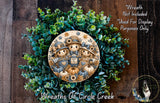 a wreath with a central design of three scarecrow figures, surrounded by a lush green wreath. The wreath is displayed on a wooden surface, and there is a small dog visible in the bottom right corner of the image.