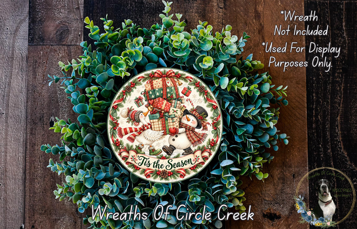a wreath with a snowman and presents, surrounded by greenery, and a decorative plate with the text "It's the Season" on it.