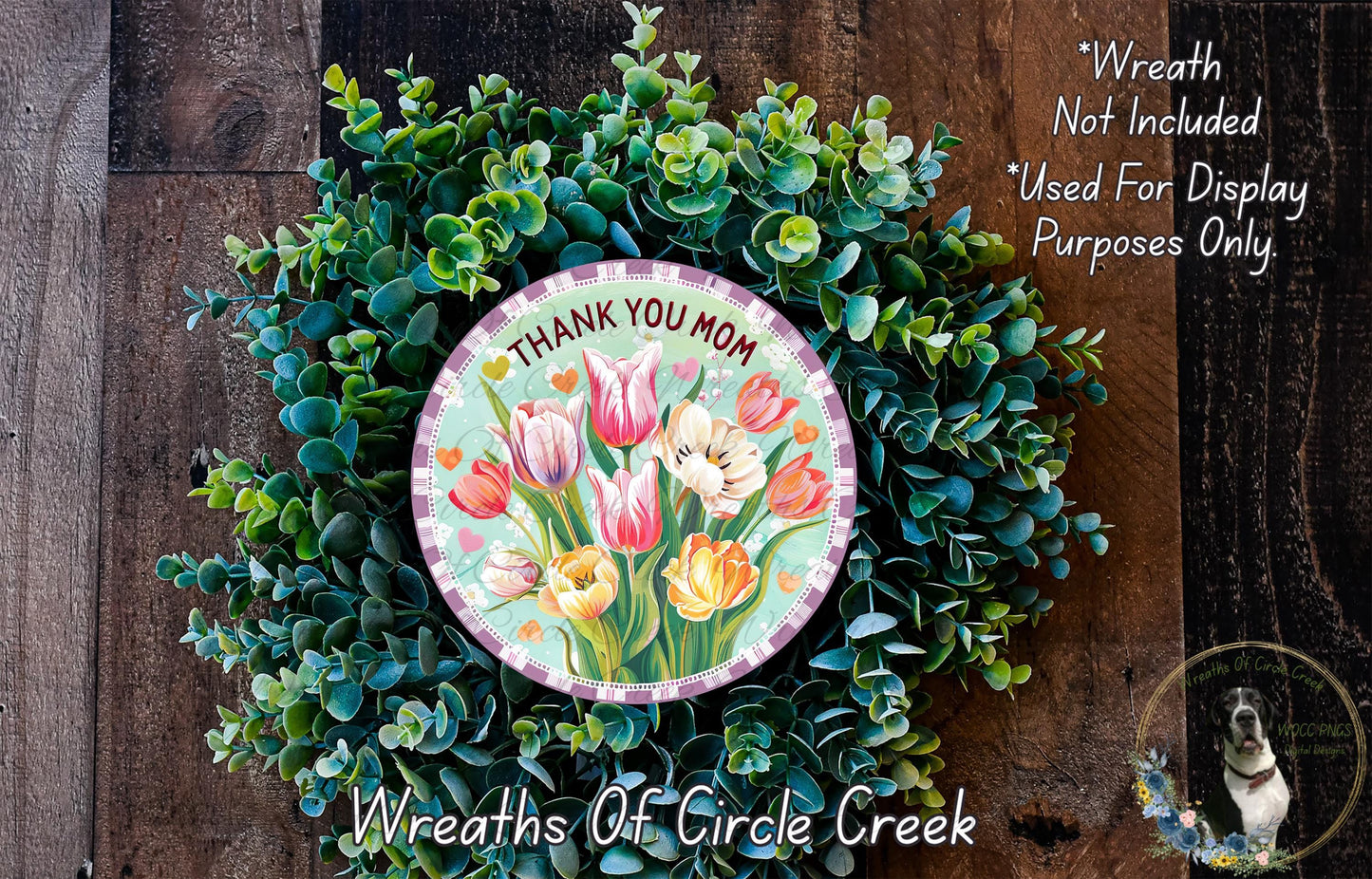A wreath made of various green plants, including tulips, placed on a wooden surface. The wreath has a circular design with a message that reads "Thank you Mom".