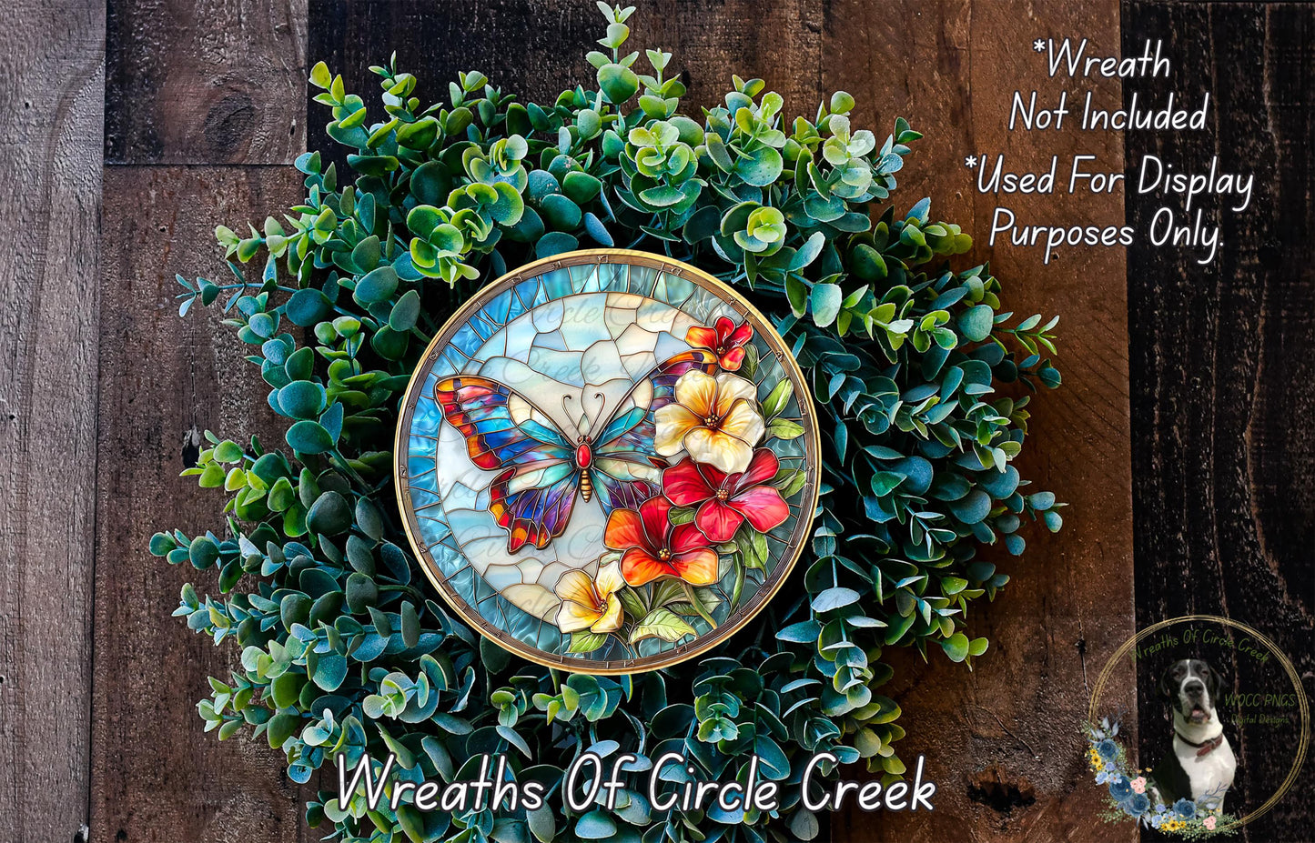 a wreath made of green foliage and colorful flowers, including a butterfly and red and yellow flowers, displayed on a wooden surface.