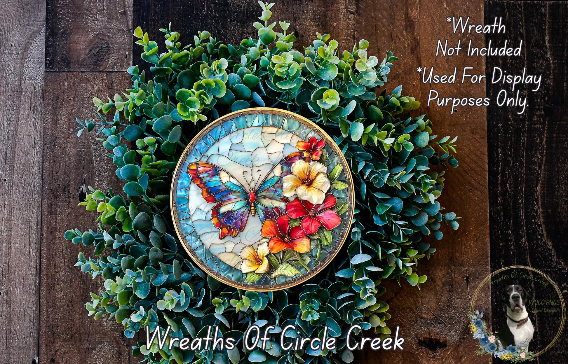 a wreath made of green foliage and colorful flowers, including a butterfly and red and yellow flowers, displayed on a wooden surface.