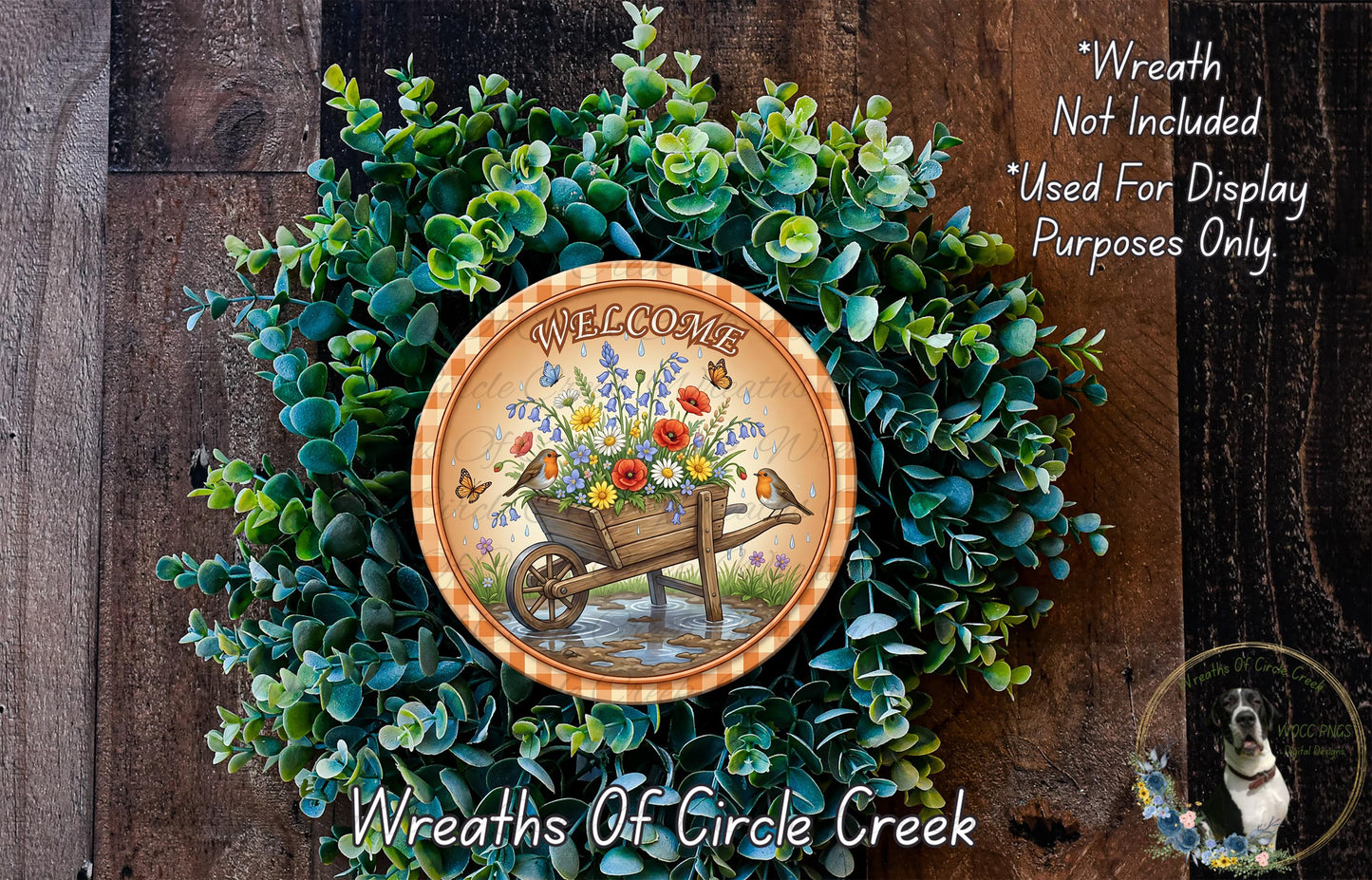 a wreath with a wooden cart filled with flowers, surrounded by greenery, and a circular sign with the text "Welcome" on it.