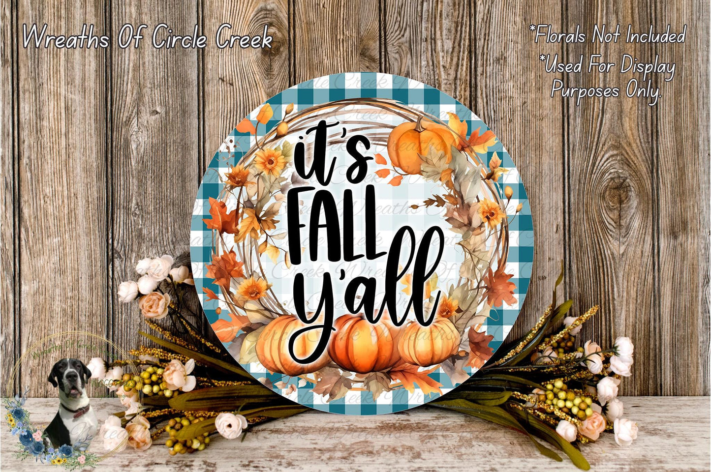 a decorative wreath with the text "It's Fall Yall" displayed on it, surrounded by autumn foliage and pumpkins. The wreath is placed on a wooden surface, and there are also some flowers and greenery in the foreground.
