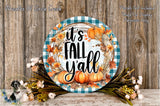 a decorative wreath with the text "It's Fall Yall" displayed on it, surrounded by autumn foliage and pumpkins. The wreath is placed on a wooden surface, and there are also some flowers and greenery in the foreground.