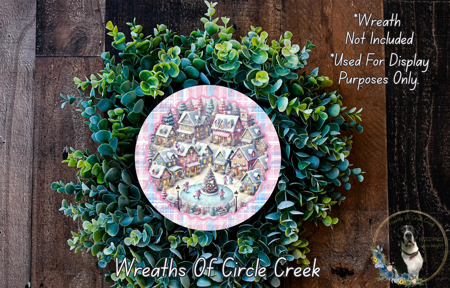 A wreath made of green foliage and a decorative plate depicting a winter village scene.