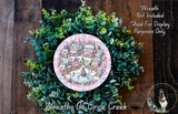 A wreath made of green foliage and a decorative plate depicting a winter village scene.