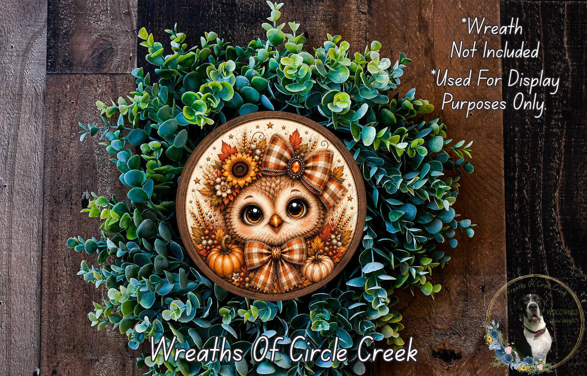 A wreath made of various green plants and a decorative owl on a wooden surface.