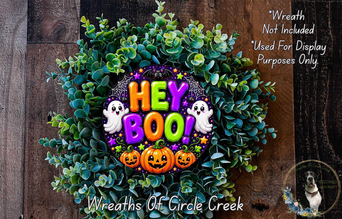 a Halloween-themed wreath made of green foliage, pumpkins, and a "HEY BOO!" sign. The wreath is displayed on a wooden surface, and there is a small dog in the bottom right corner.