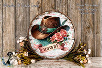 A rustic wooden sign with a decorative cowboy hat and floral accents, surrounded by a wreath of flowers and greenery.