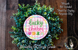 a wreath made of green leaves and a circular sign with the text "lucky charm" on it, placed on a wooden surface.