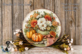 A decorative wreath with a floral arrangement of orange and white flowers, surrounded by pumpkins and other fall-themed elements, displayed on a wooden surface.